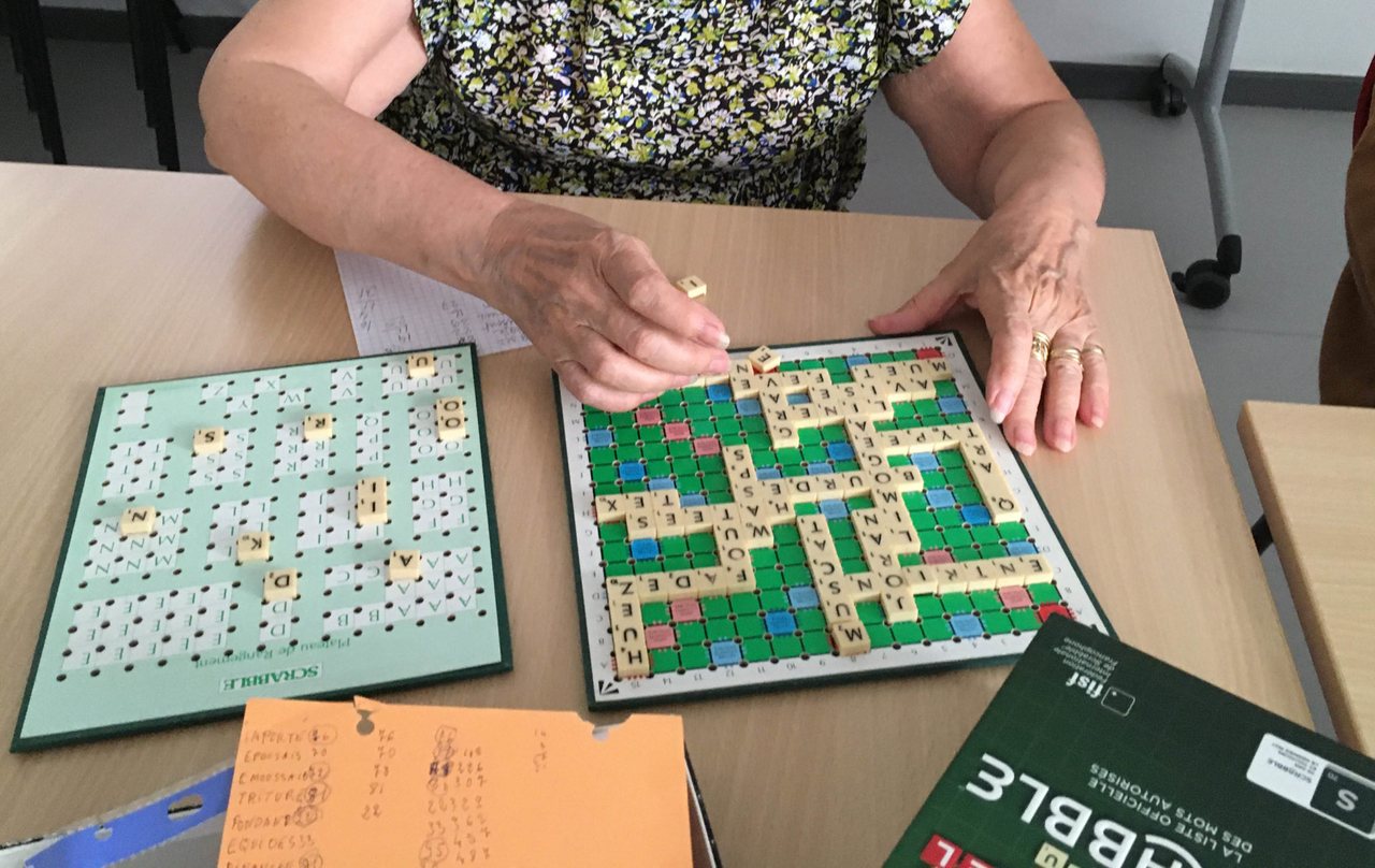 Partie de Scrabble organisée en salle avec des joueuses autour d’une table